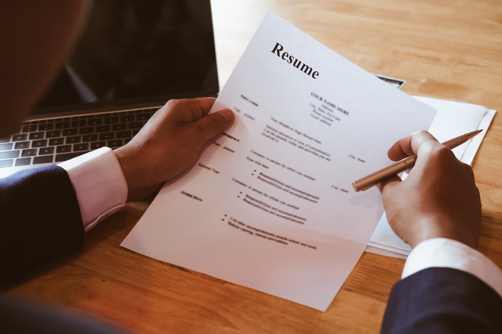 HR Manager Reviewing Resume Information on His Wooden Desk